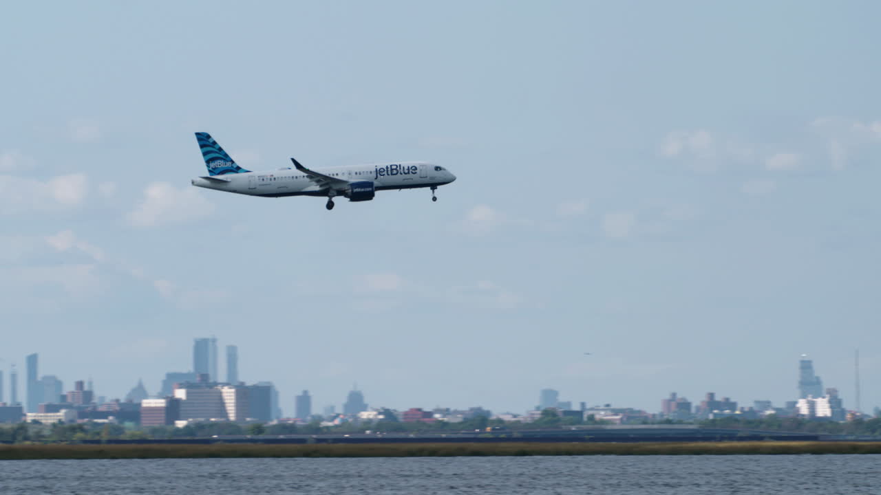 Camera Panning to Follow JetBlue Airlines Plane Passing Manhattan Skyline to Land at JFK Airport