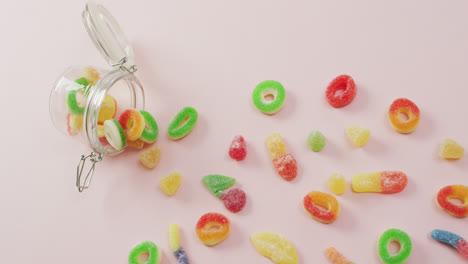 video of colourful jelly candy and jar on pink background