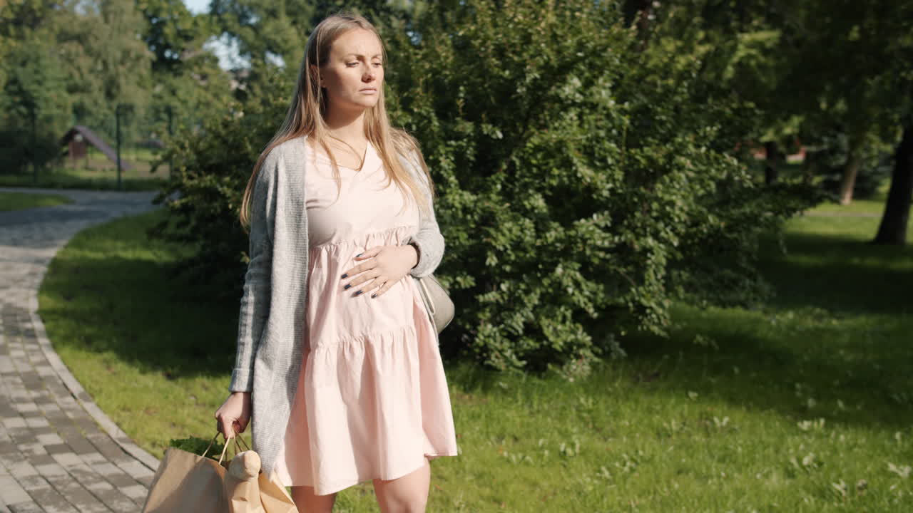 Pregnant Woman Walking in Park with Groceries
