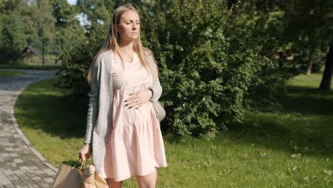 pregnant woman walking in park with groceries