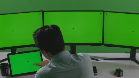 여러 그린 스크린 모니터에서 일하는 사업가