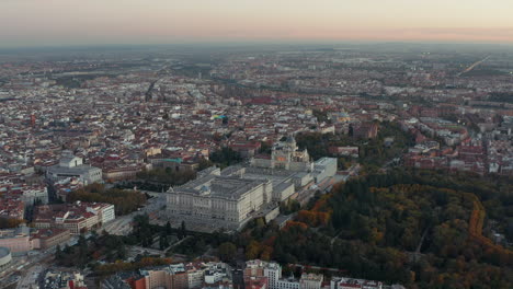 Descending-footage-of-Royal-Palace-and-Almudena-Cathedral-at-dusk.-Aerial-panoramic-footage-of-city-with-historic-landmarks.