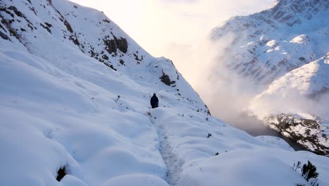 solo backpacker, trekking through thick blanket of snow over mountains on routeburn track