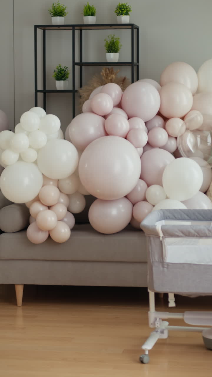 Globos de colores pastel suaves crean un telón de fondo festivo para un baby shower con un moisés cerca.