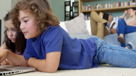 Brother-and-sister-using-laptop-on-the-floor