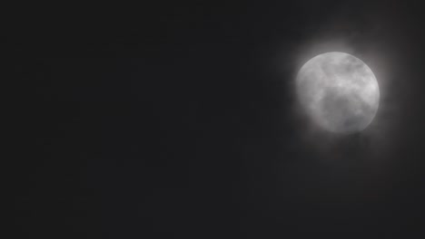 luna brillante con nubes que la cubren contra el cielo oscuro