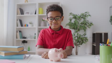 smiling black boy putting coin in piggybank, financial literacy for kids, money