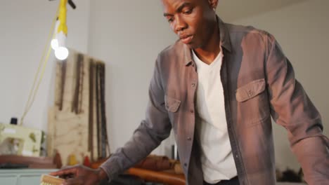 focused african american craftsman brushing leather in leather workshop