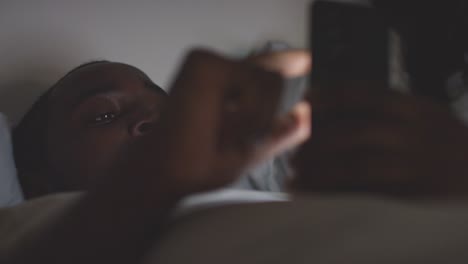 Primer-Plano-De-Una-Pareja-En-Casa-Por-La-Noche,-Ambos-Mirando-Sus-Teléfonos-Móviles-En-La-Cama