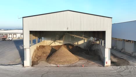 industrial chicken farm with large white sheds, a gravel mound, and a spacious paved area for operations, set against a clear sky