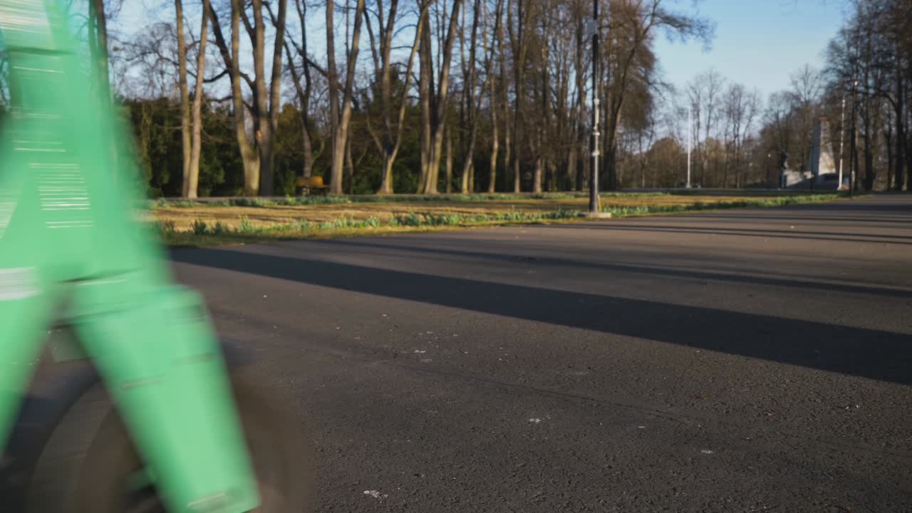 전기 스쿠터를 탄 남자가 카메라 앞에서 왼쪽에서 오른쪽으로 지나간다