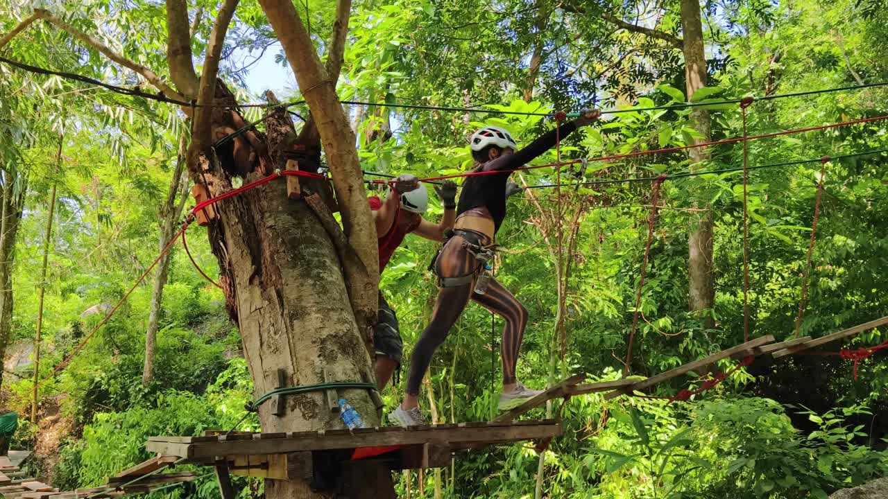 Couple enjoying a treetop adventure course in a tropical forest