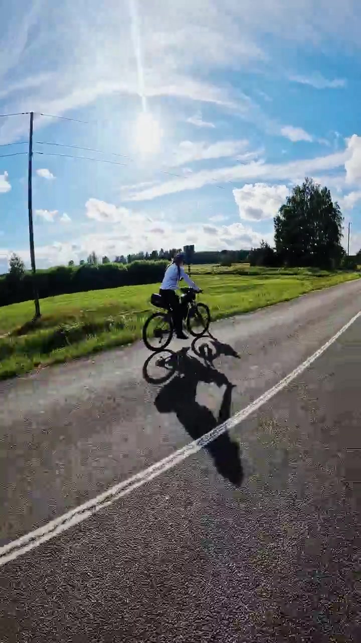 Ciclista avventuroso esplora le panoramiche strade secondarie baltiche sotto un cielo estivo splendente.