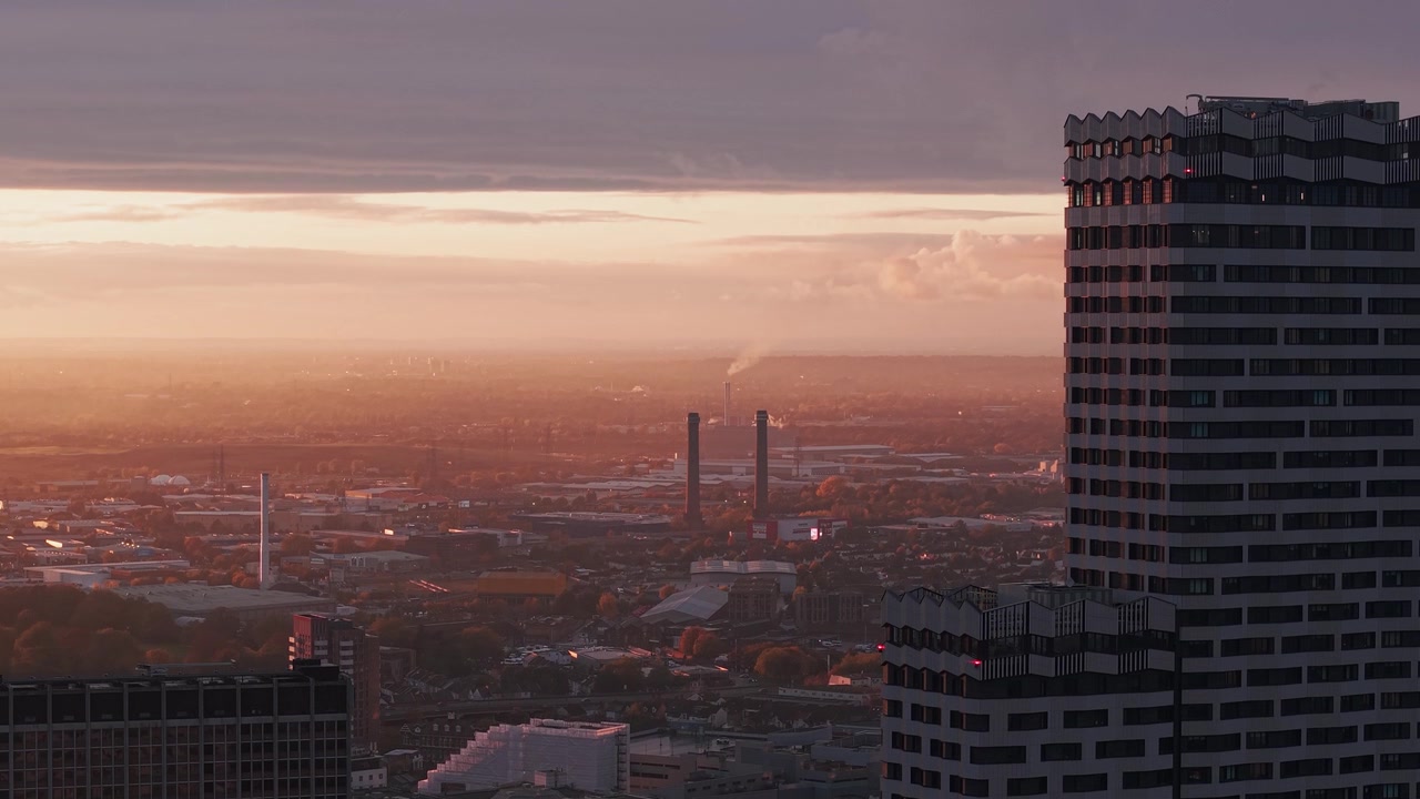 Vista aérea subindo blocos residenciais altos de Croydon para revelar uma paisagem urbana matinal dourada e nebulosa.