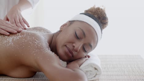 mujer recibiendo un tratamiento de exfoliación con sal