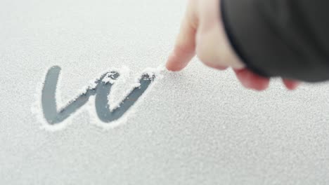 pov person writing word winter on car window in snow with finger