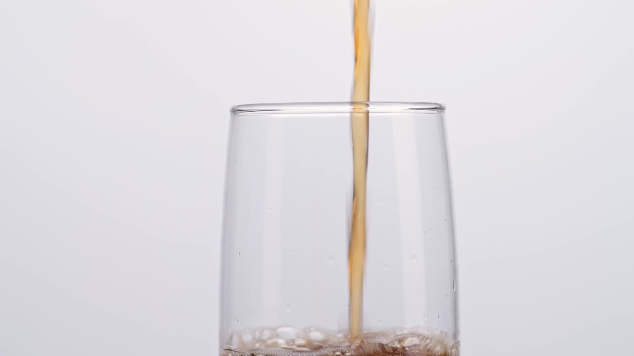 Close Up Of Fresh Cola Being Poured In To The Glass On White Background