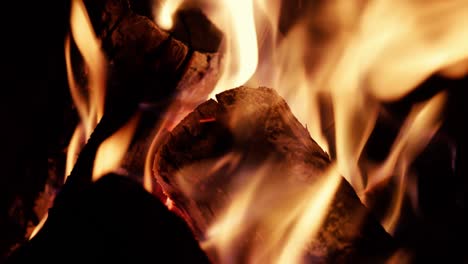 detalles con madera y brasas quemándose en un pozo de fuego de campamento por la noche.