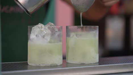 refreshing cocktail being poured into glassware, held delicately by one hand