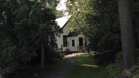 Approaching-a-heritage-school-house-from-a-path-surrounded-by-trees-in-Ottawa,-Canada-at-the-Strathmere-Resort