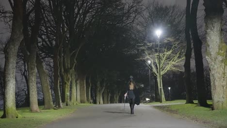 a young female child dressed for halloween as a plague doctor walks in between trees at night