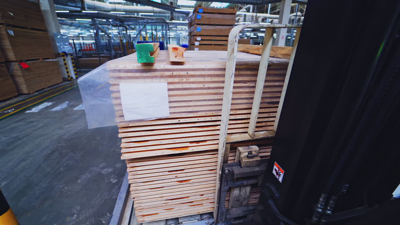 Factory of laminate production. Forklift truck taking a pile of wooden pallets. Interior of warehouse of a parquet board production.