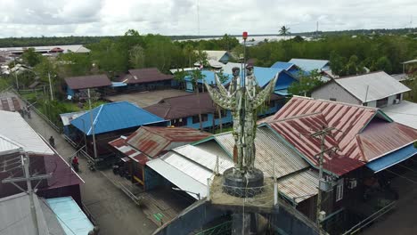 the beautiful hand monument and local houses stand on top of the city of agats, asmat, papua, indonesia