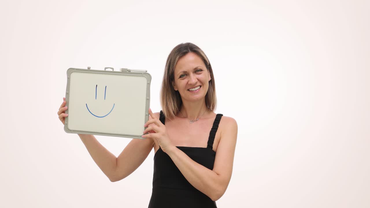 Smiling woman holding a whiteboard with a happy face drawing