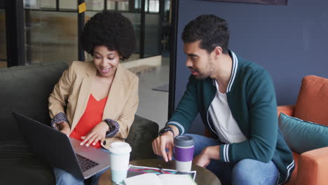 diverse business people sitting going through paperwork using laptop in a modern office