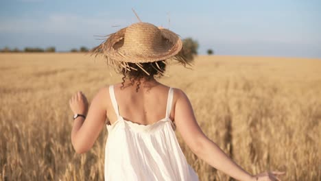 Tracking-Footage-Of-A-Beautiful-Girl-In-White-Summer-Dress-And-Straw-Hat-Running-Freely-By-Wheat-Field