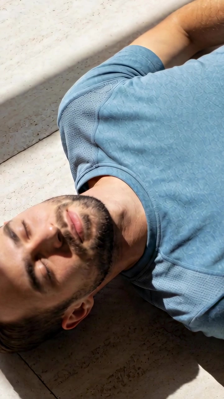 Vertical video: Lying adult male shifting head on tiled floor near light wall, reacting to sunbeam
