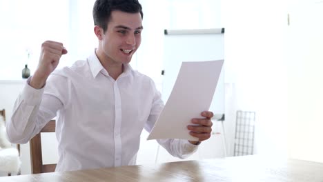 successful businessman reading documents and celebrating win