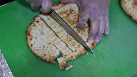 Koch,-Der-Türkisches-Brot-Auf-Einem-Schneidebrett-Schneidet,-Nahaufnahme-Des-Kochs,-Der-Brot-In-Zeitlupe-Schneidet-1