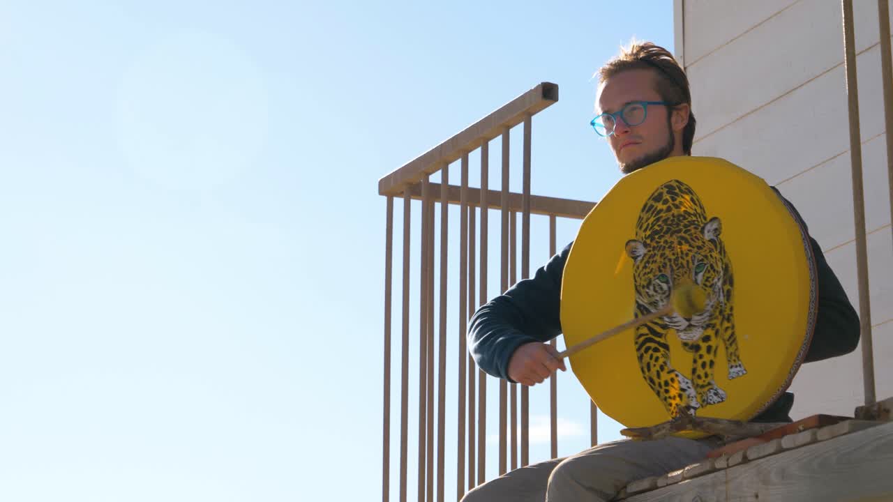 이 비는 날에 밖에서 앉아서 막대기로 드럼에 부히는 사람, 드럼 표면에 호랑이 그림, 자유와 개인 표현 개념