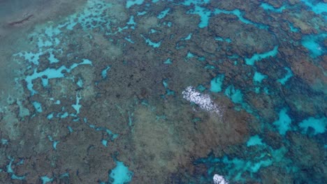 una vista de pájaro proporcionada por el dron muestra la idílica laguna azul, su transparencia revela la belleza oculta de las rocas y la vida marina, mientras las olas rompen contra el arrecife