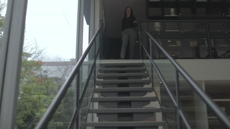 middle aged adult woman walks down stairs in modern style home