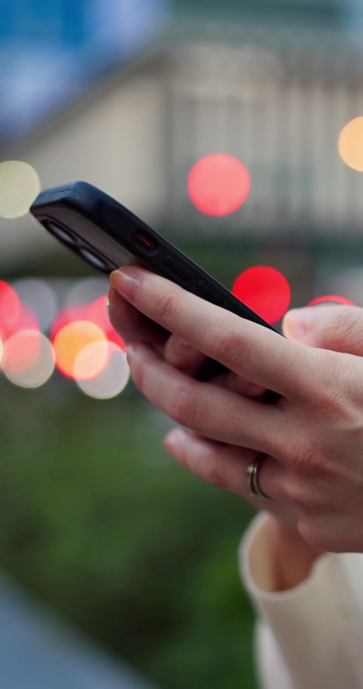 Primo piano di donna che usa lo smartphone all'aperto di notte