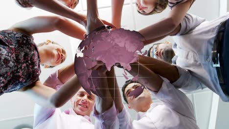 animation of globe rotating over happy diverse colleagues stacking hands at casual office