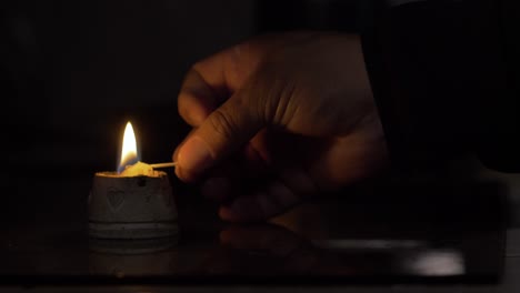 lighted-candle-in-the-dark,-candle-lights-up-a-room-with-unfocused-background