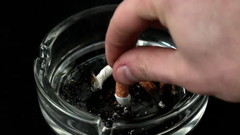 hand putting out a cigarette in ashtray