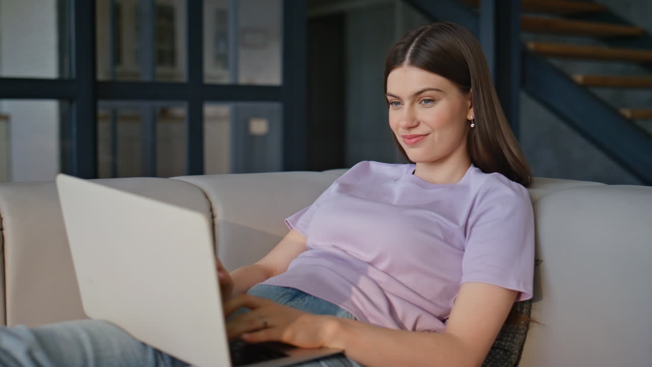 Relaxed lady sending email using laptop at couch closeup. Woman texting computer