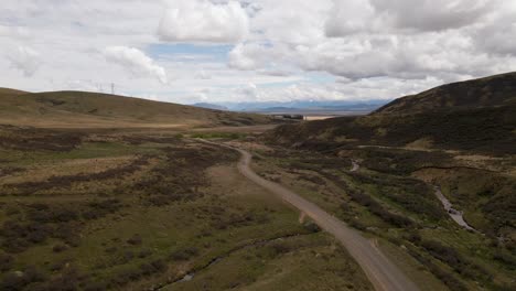 Aerial-follow-shot---car-travelling-along-mountain-pass-road-between-hills-and-pastures