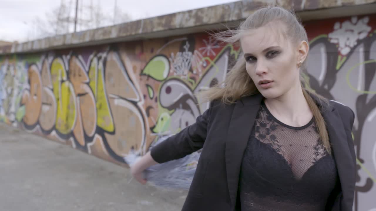 그래피티 벽을 향해 포즈를 취하는 세련된 여성