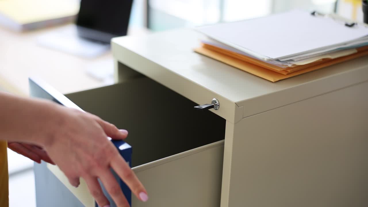 Person unlocking and opening a blue filing cabinet