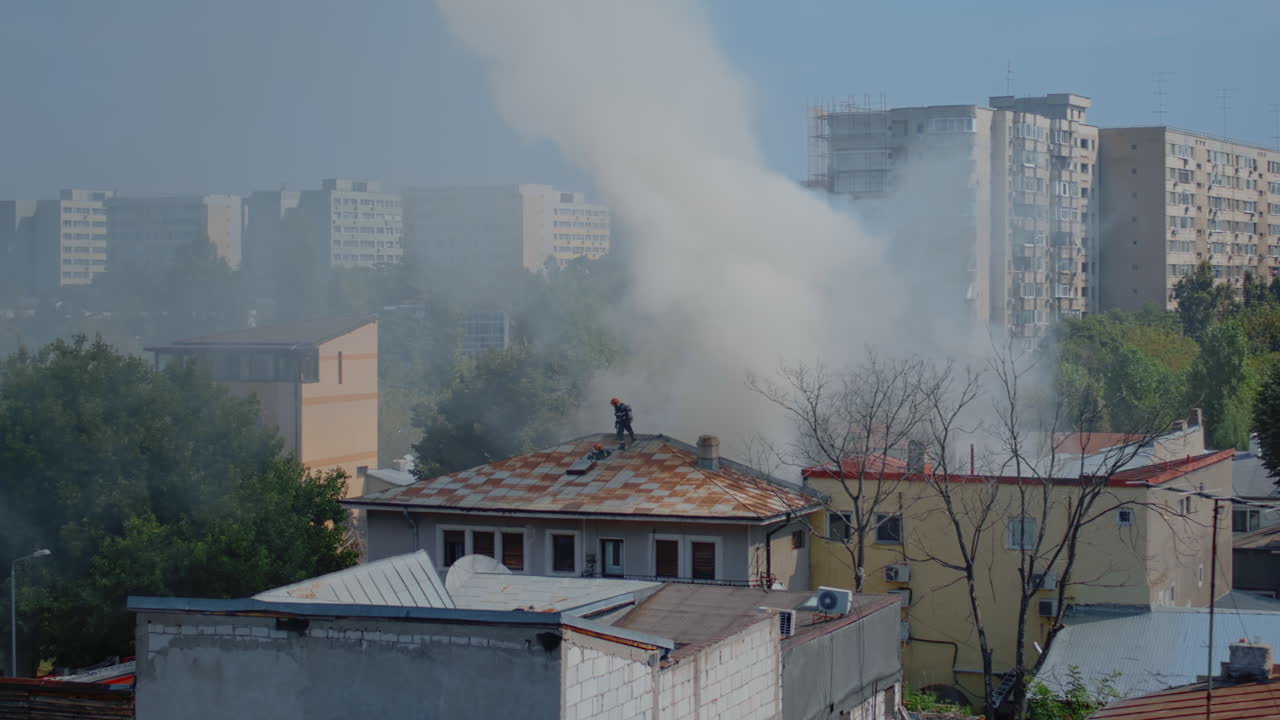 Firefighters on roof of burning house trying to extinguish flames