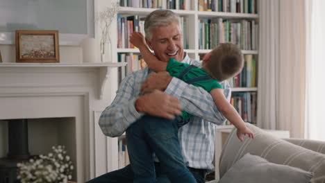 happy little boy hugging grandfather playfully jumping into grandad's arms having fun enjoying weekend with grandparent at home
