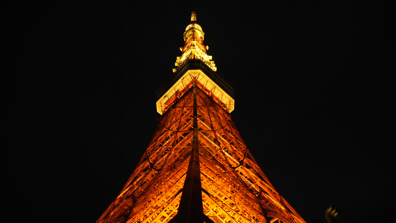 Tilt up shot, under the Tokyo tower, at night time, in Minato, Japan