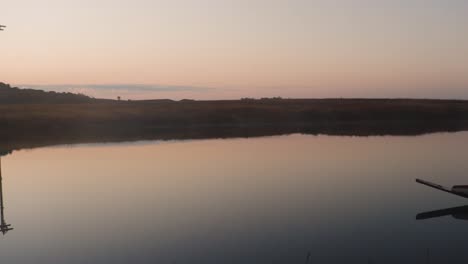 Ruhiges-Seewasser-Mit-Traditionellem-Holzboot-Und-Sonnenaufgang-Dramatischer-Orangefarbener-Himmel-Am-Morgen