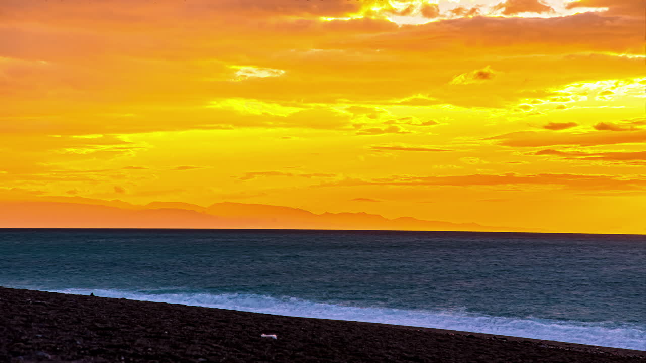 모래사장에 부서지는 바다 파도와 함께 어두운 하늘에서 밝은 하늘로 노란 하늘 위로 타임랩스의 일출