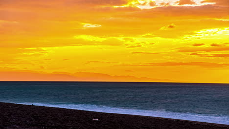 Sunrise-in-timelapse-over-yellow-sky-from-dark-to-bright-sky-with-sea-waves-crashing-on-the-sandy-beach